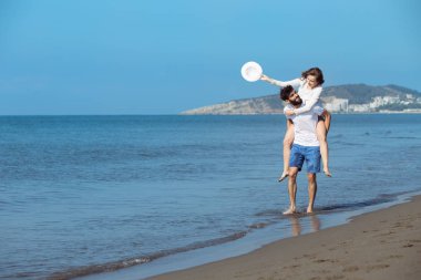 Bir kız plajda sırtında taşıyan bir adam