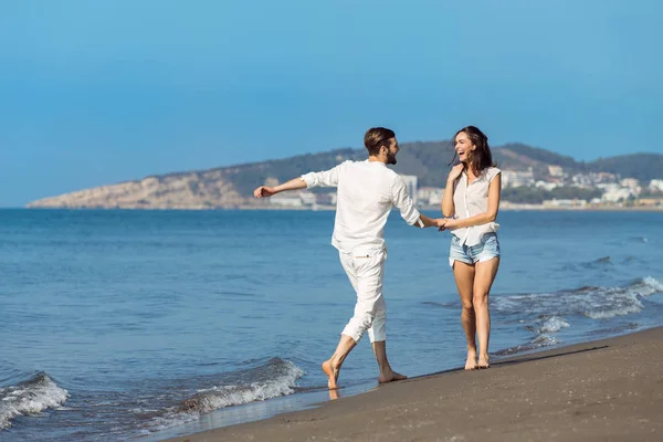 Jong koppel wandelen op het strand glimlachen — Stockfoto