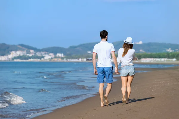 Jeune couple marchant sur la plage — Photo