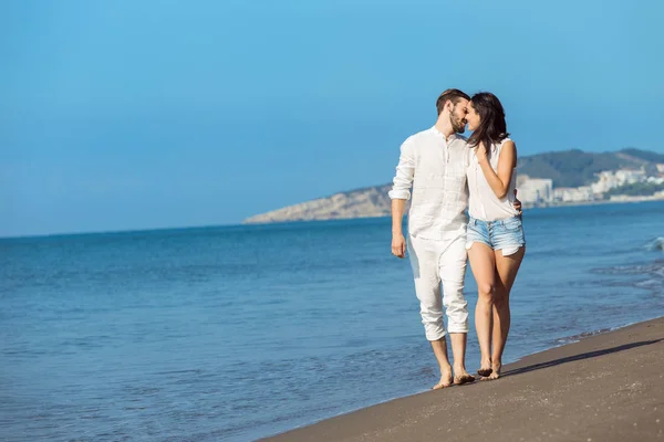 Pasangan muda berjalan di pantai tersenyum — Stok Foto