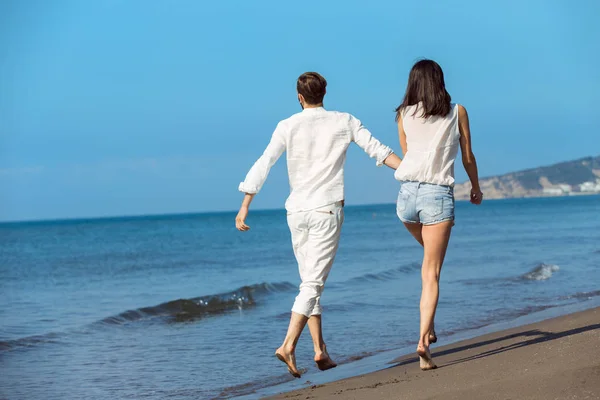 Ungt par promenader på stranden leende — Stockfoto