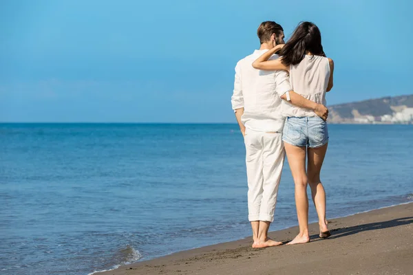 Jong koppel wandelen op het strand glimlachen — Stockfoto