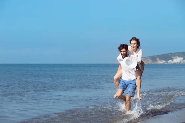 Seorang pria membawa seorang gadis di pantai — Stok Foto