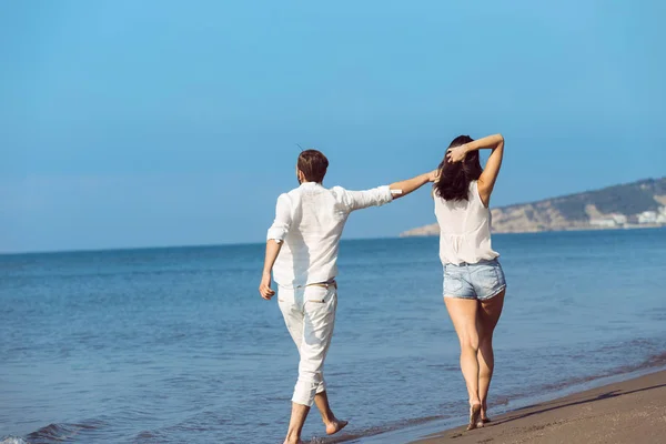 Jovem casal andando na praia sorrindo — Fotografia de Stock