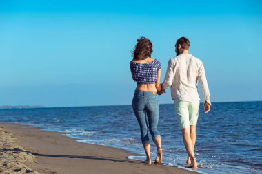 Sahilde yürüyen ırklar arası genç bir çift..