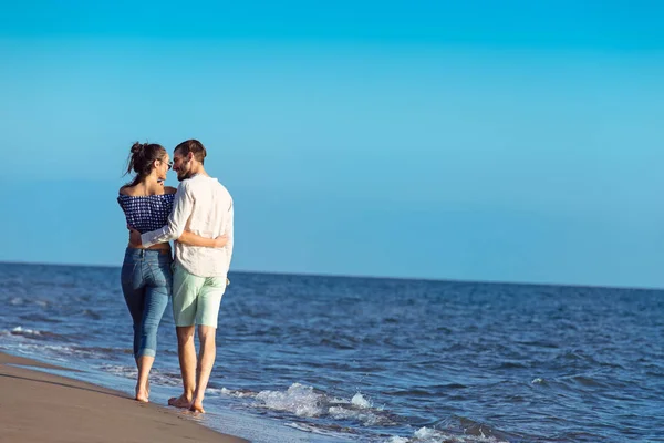 Feliz casal interracial andando na praia . — Fotografia de Stock