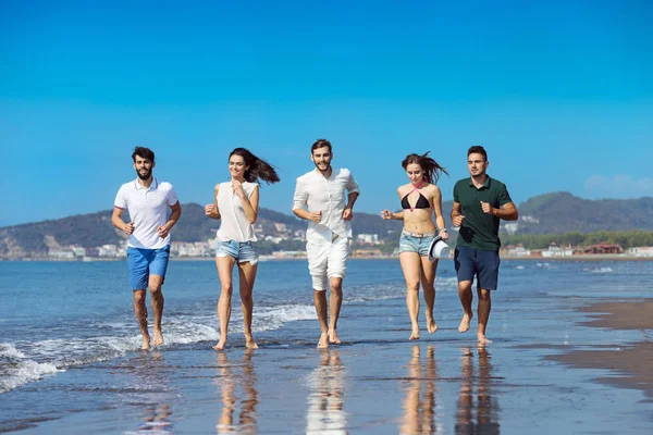 Grupo de jovens que correm na praia — Fotografia de Stock