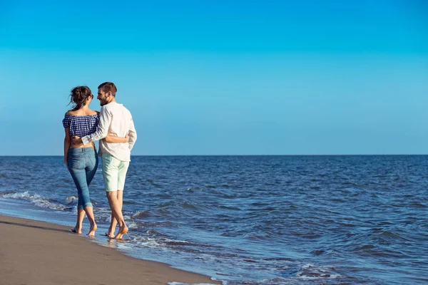 Feliz casal interracial andando na praia . — Fotografia de Stock
