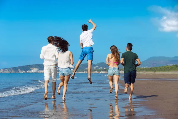 Skupina mladých lidí běží na pláži — Stock fotografie