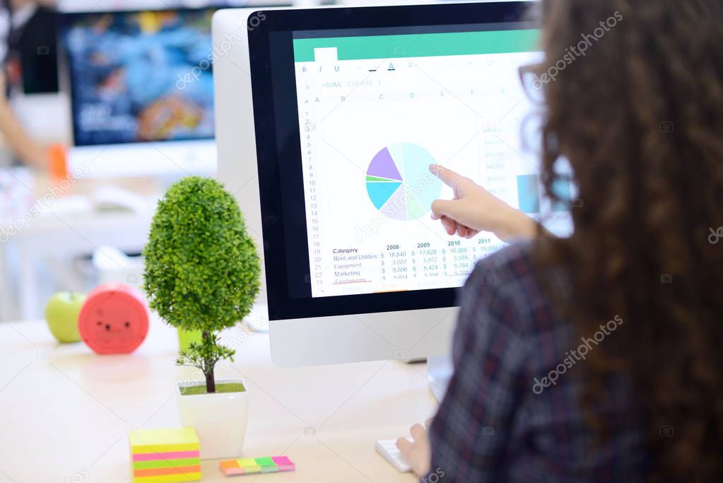 businesswoman working at computer and pointing to graph