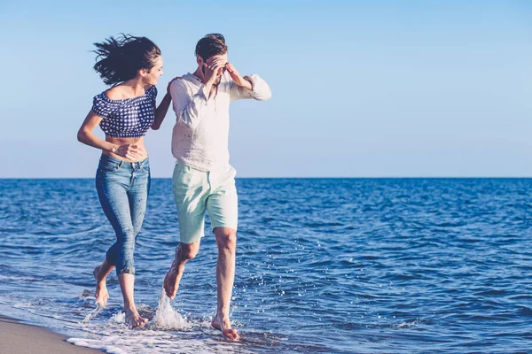 Casal feliz correndo na praia — Fotografia de Stock