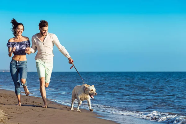 Glückliches Paar mit Hund am Strand — Stockfoto