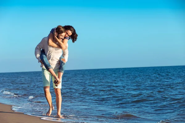 男は浜のガール フレンドに与えるおんぶ — ストック写真
