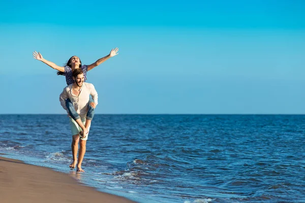 Hombre dando cerdito espalda a novia en la playa —  Fotos de Stock