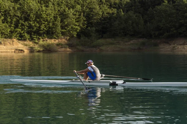 Joven solo scull remando en el lago — Foto de Stock