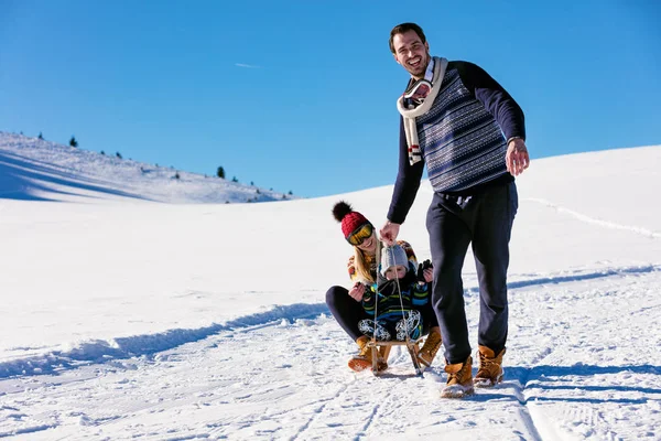 Семья с ребенком на санях зимой — стоковое фото