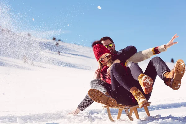 Молодая пара катается на санках зимой — стоковое фото