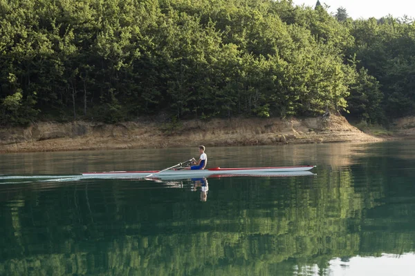 Joven solo scull remando en el lago — Foto de Stock