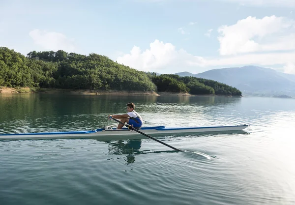 Joven solo scull remando en el lago — Foto de Stock