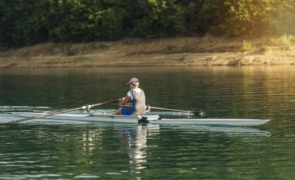 Joven solo scull remando en el lago — Foto de Stock