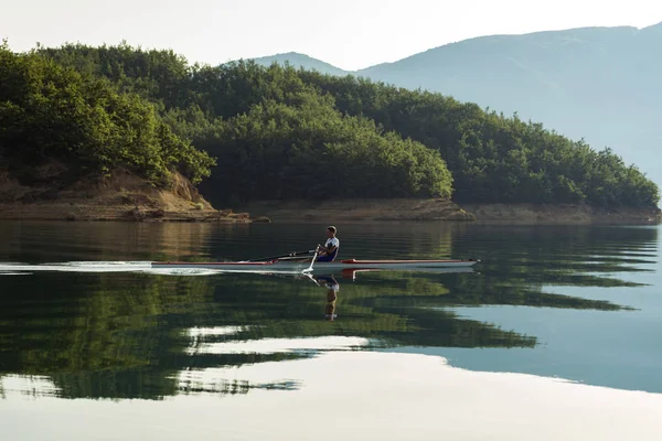 Joven solo scull remando en el lago — Foto de Stock