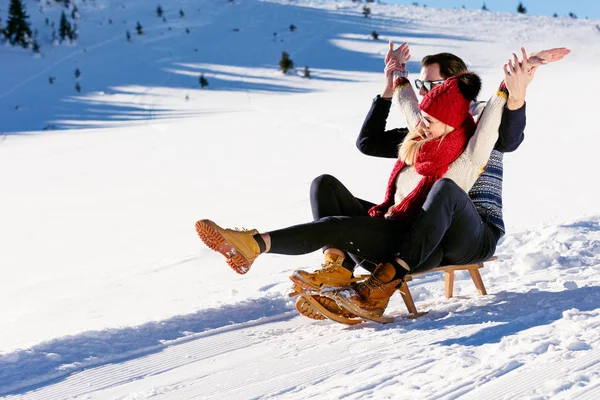 Молодая пара катается на санках зимой — стоковое фото