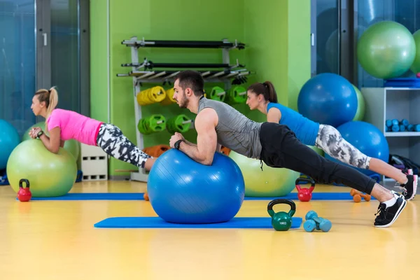 group exercising on Swiss ball at gym