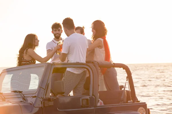 Люди, развлекающиеся в машине на пляже — стоковое фото