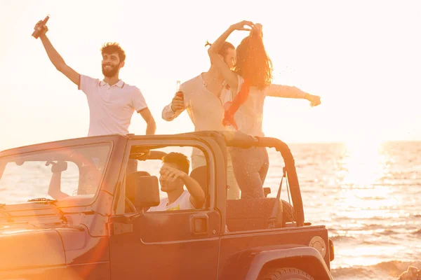 Menschen amüsieren sich im Auto am Strand — Stockfoto