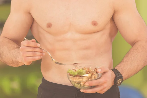 bodybuilding man holding a fresh salad