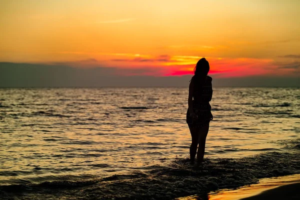 Smyslná žena při východu slunce na pláži — Stock fotografie