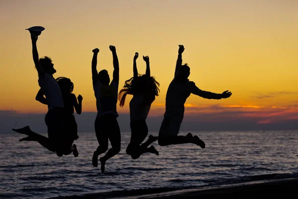 Silhouette di amici che saltano sulla spiaggia — Foto Stock