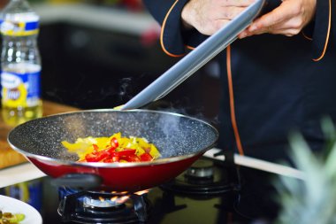 Şef sebzeler tavada karıştırma