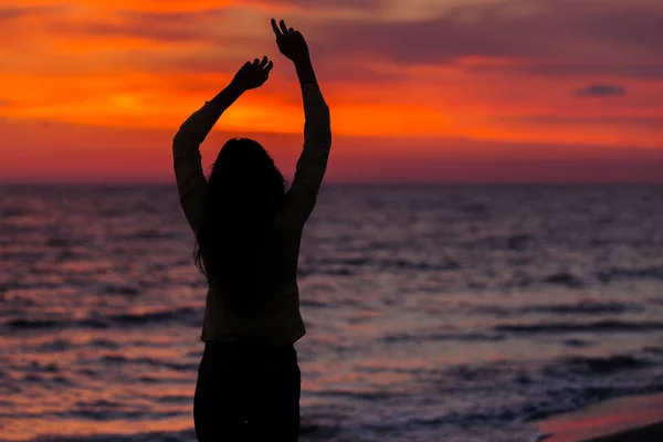 Jovem de pé contra o pôr do sol — Fotografia de Stock