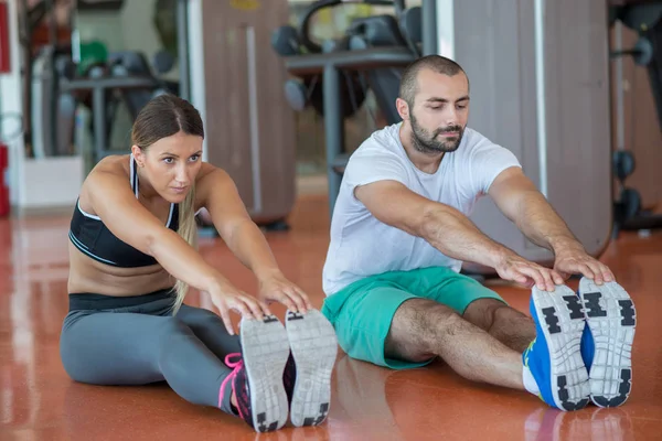 Frau dehnt sich mit Trainer — Stockfoto