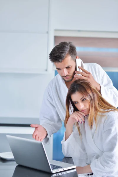 Pareja en la cocina usando un ordenador portátil — Foto de Stock