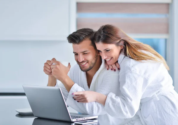 Pareja en la cocina usando un ordenador portátil — Foto de Stock