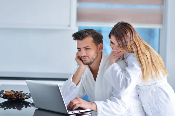 Pareja en la cocina usando un ordenador portátil — Foto de Stock