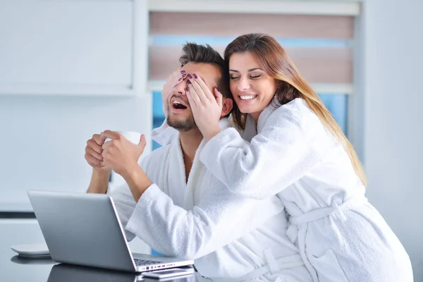 Pareja en la cocina usando un ordenador portátil — Foto de Stock