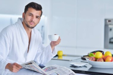 Bornoz mutfak üzerinde oturan genç adam 