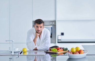 Bornoz mutfak üzerinde oturan genç adam 