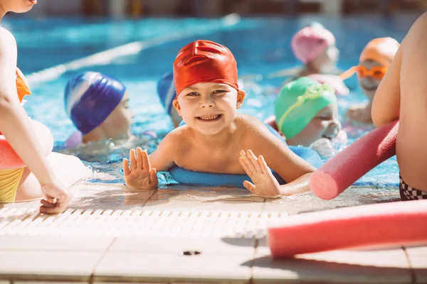 Glückliche Kindergruppe im Schwimmbad lernt schwimmen — Stockfoto