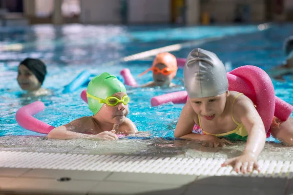 Glückliche Kindergruppe im Schwimmbad lernt schwimmen — Stockfoto