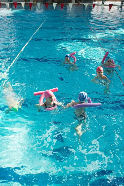 Щасливі діти групуються в класі басейну, навчаючись плавати — стокове фото