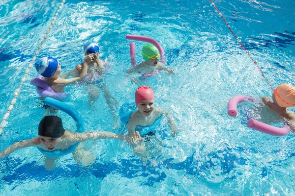 Glückliche Kindergruppe im Schwimmbad lernt schwimmen — Stockfoto