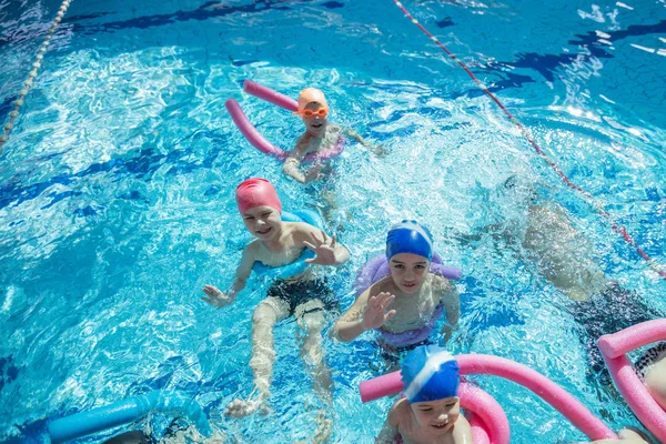 Glada barn barn gruppen vid poolen klass att lära sig att simma — Stockfoto