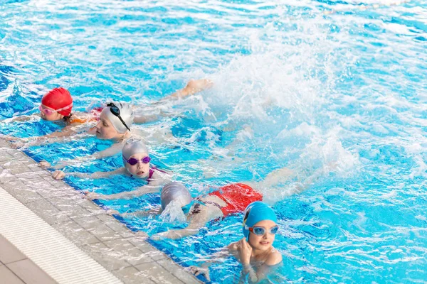 Щасливі діти групуються в класі басейну, навчаючись плавати — стокове фото