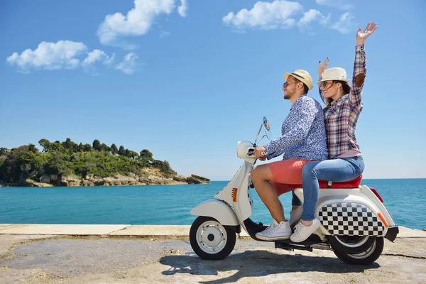 Hermosa pareja joven enamorada disfrutando y divirtiéndose montando en una scooter en una hermosa naturaleza — Foto de Stock