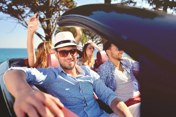 Ocio, viaje por carretera, viajes y concepto de personas - amigos felices conduciendo en coche cabriolet a lo largo de la carretera del país — Foto de Stock