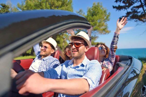 Ocio, viaje por carretera, viajes y concepto de personas - amigos felices conduciendo en coche cabriolet a lo largo de la carretera del país — Foto de Stock